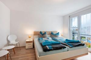 Un dormitorio con una cama con almohadas azules y una ventana. en Haus Haldenweg, en Höchenschwand