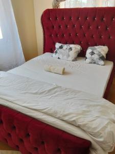 a red bed with a red headboard and white sheets at Swahiba's 254 in Keruguya