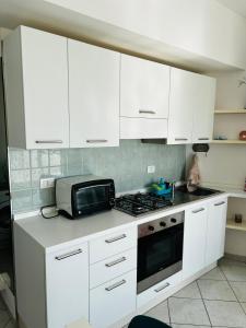 a kitchen with white cabinets and a microwave at Searoom in Lido delle Nazioni