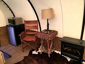 a living room with a chair and a table with a lamp at Amazing Conestoga Wagon for the Perfect Forest Getaway near Bryce Canyon, Utah in Alton