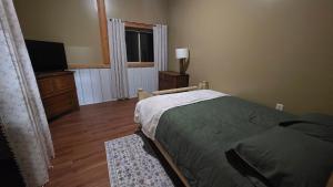 a bedroom with a bed and a television and a window at The Alderwood Lodge 
