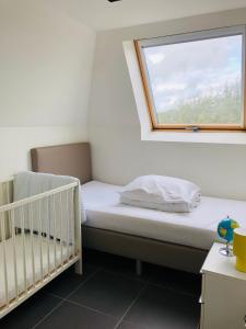 a small bedroom with a crib and a window at Vakantiehuis De Panne in De Panne
