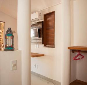 a kitchen with a microwave and a window at Casa Marrocos Arraial d'Ajuda in Arraial d'Ajuda