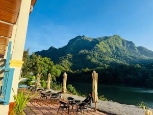 Una mujer sentada en un patio con vista a un lago. en Sabaidee Nam Ou River View, en Nongkhiaw