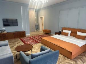 a bedroom with a bed and a couch and a tv at Boutique Hotel "White HiLL" in Aktau
