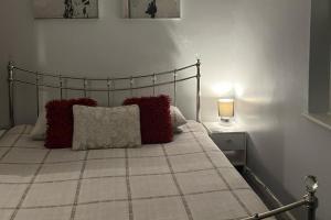 a bedroom with a bed with red pillows and a lamp at 1-Bedroom Apartment Sleeps 4 Parking in Hythe