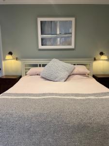 a bedroom with a bed with two lamps and a window at Stunning Countryside House with Pool and Hot Tub in Hankerton +22 photos