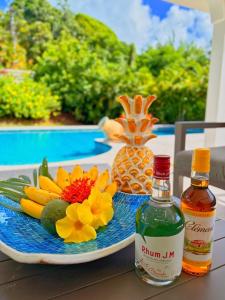 a table with a plate with a bottle of alcohol and flowers at Domaine Du Paradis in Le Robert