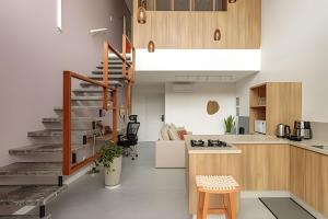 a kitchen and living room with a staircase in a house at Loft Moderno, 500m Praia, Piscina, Sauna, WiFi 1GB in Florianópolis