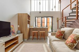 a living room with a couch and a kitchen at Loft Moderno, 500m Praia, Piscina, Sauna, WiFi 1GB in Florianópolis