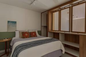 a bedroom with a large bed with pillows at Loft Moderno, 500m Praia, Piscina, Sauna, WiFi 1GB in Florianópolis +18 photos