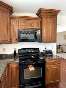 een keuken met houten kasten en een zwarte kookplaat bij 11-Acre Retreat I Firepit, Pickleball and Nature 