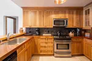 a kitchen with wooden cabinets and stainless steel appliances at Skycrest Penthouse 1733 in Big Sky +21 photos
