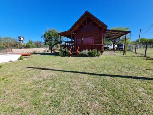 une petite cabine dans un champ avec une pelouse dans l'établissement Cabañas en Los Reartes Córdoba, à Villa General Belgrano