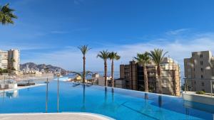 a large swimming pool with palm trees and buildings at SUNSET CLIFFS fantastic apartment in Benidorm