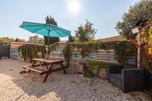 a picnic table with an umbrella next to a fence at Maison Mexico in Saint-Mitre-les-Remparts