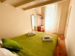 Mediterranean House With Amalfi Coast View في Colli di Fontanelle: غرفة نوم بسرير اخضر عليها منشفتين
