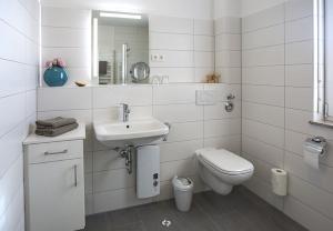 a white bathroom with a sink and a toilet at WINDLICHT App Nr 3 max 4 Pers in Dierhagen +3 photos