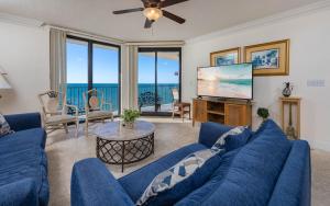 Phoenix X 1513 condo في شاطئ أورانج: غرفة معيشة مع أريكة زرقاء وتلفزيون بشاشة مسطحة