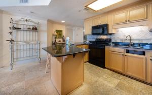 Phoenix X 1513 condo في شاطئ أورانج: مطبخ مع خزائن خشبية وطاولة عمل