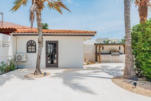 a white house with palm trees in front of it at Walk to Palm Beach! 5Bed Hottub with Pool 10people in Palm-Eagle Beach