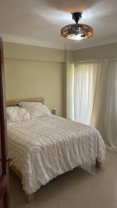 - une chambre avec un lit doté d'une couette blanche et d'une fenêtre dans l'établissement Marvilla - Coastal Condo Poolside & Ocean View, à Boca Chica