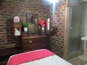 a brick walled bathroom with a dresser and a mirror at Pumba's B&B in Sannieshof