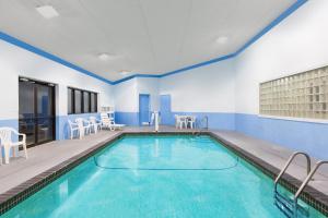 a pool in a room with chairs and tables at Days Inn & Suites by Wyndham Des Moines Airport in Des Moines