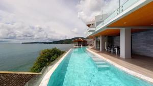 a building with a swimming pool next to the water at Cape Sienna Villa 4-Oceanfront 5-Bedroom Luxury Villa with 22 m Infinity Pool in Kamala Beach