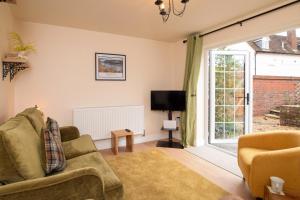 un salon avec un canapé, une télévision et une fenêtre dans l'établissement No Road - The Cottage, à Bewdley