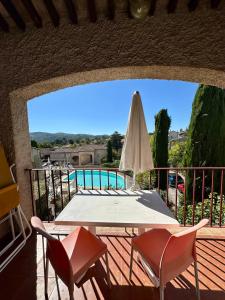 un patio con una mesa y una sombrilla blanca en Le Mas de l'Orangerie 3 etoiles, en Gréoux-les-Bains
