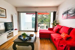 a living room with a red couch and a table at Le Navire-Plage du Nau-Parc-Résidence calme-Garage in Le Pouliguen