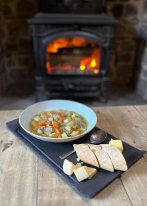 a plate of soup with bread and a plate of cheese at Suite 12 - Sleeping Giant Hotel - Pen Y Cae Inn in Brecon