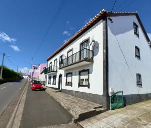 a red car parked next to a white building at Biscoitos-Upstudio in Biscoitos