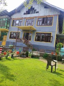a blue and yellow house with a bench in the yard at Residence Inn Home Stay in Pahalgām