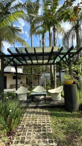 a wooden pergola with two benches and palm trees at Pousada Costeira Barra do Sul in Balneario Barra do Sul