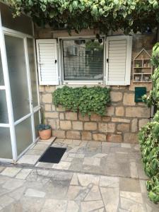 a building with two windows and a stone wall at Apartment Get in Supetar