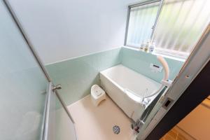 Un baño con bañera, inodoro y ventana. en 駅徒歩6分 4ldk 82平米 最大8人 成田空港から約40分 和と洋の美しい室内 隠れ家 せつきの宿, en Matsudo 31 fotos más