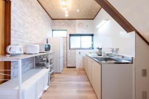 una cocina con fregadero y refrigerador en 駅徒歩6分 4ldk 82平米 最大8人 成田空港から約40分 和と洋の美しい室内 隠れ家 せつきの宿, en Matsudo