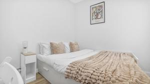a white bedroom with a bed with a blanket at Stylish 2-Bed flat in E17 in London +1 photo