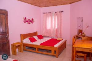 een slaapkamer met een houten bed met rode kussens bij Kambana Résidence in Ranomafana