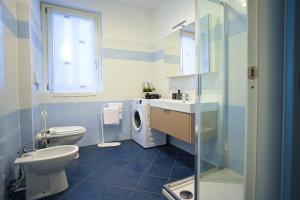 a bathroom with a toilet and a sink and a washing machine at Tra la Rocca e il lago in Angera