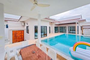 une piscine dans une maison avec une table et des chaises dans l'établissement Luekpanee pool villa pranburi, à Ban Nong Ban Kao