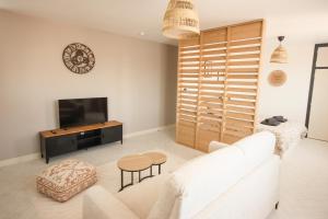 un salon avec un canapé blanc et une télévision dans l'établissement Le Soy'ô - Parking - Mairie - Angoulême à 10 min, à Soyaux