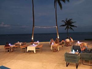 a group of people sitting at tables on the beach at ThreeTreesSamuiPoolVilla in Ban Thung