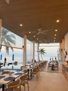 a restaurant with tables and a view of the beach at ThreeTreesSamuiPoolVilla in Ban Thung