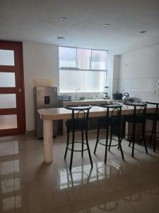 a kitchen with three bar stools and a counter top at Apartment, with kitchen, garage and laundry in Tacna