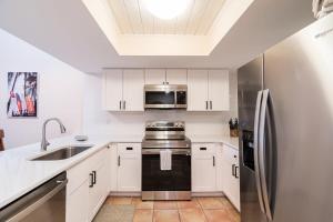 een keuken met witte kasten en een roestvrijstalen koelkast bij Beach Townhome Steps from Downtown Cocoa Beach in Cocoa Beach