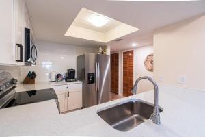 een keuken met een spoelbak en een roestvrijstalen koelkast bij Beach Townhome Steps from Downtown Cocoa Beach in Cocoa Beach