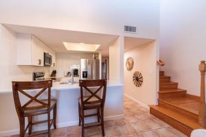 een keuken met 2 stoelen en een aanrecht met een wastafel bij Beach Townhome Steps from Downtown Cocoa Beach in Cocoa Beach